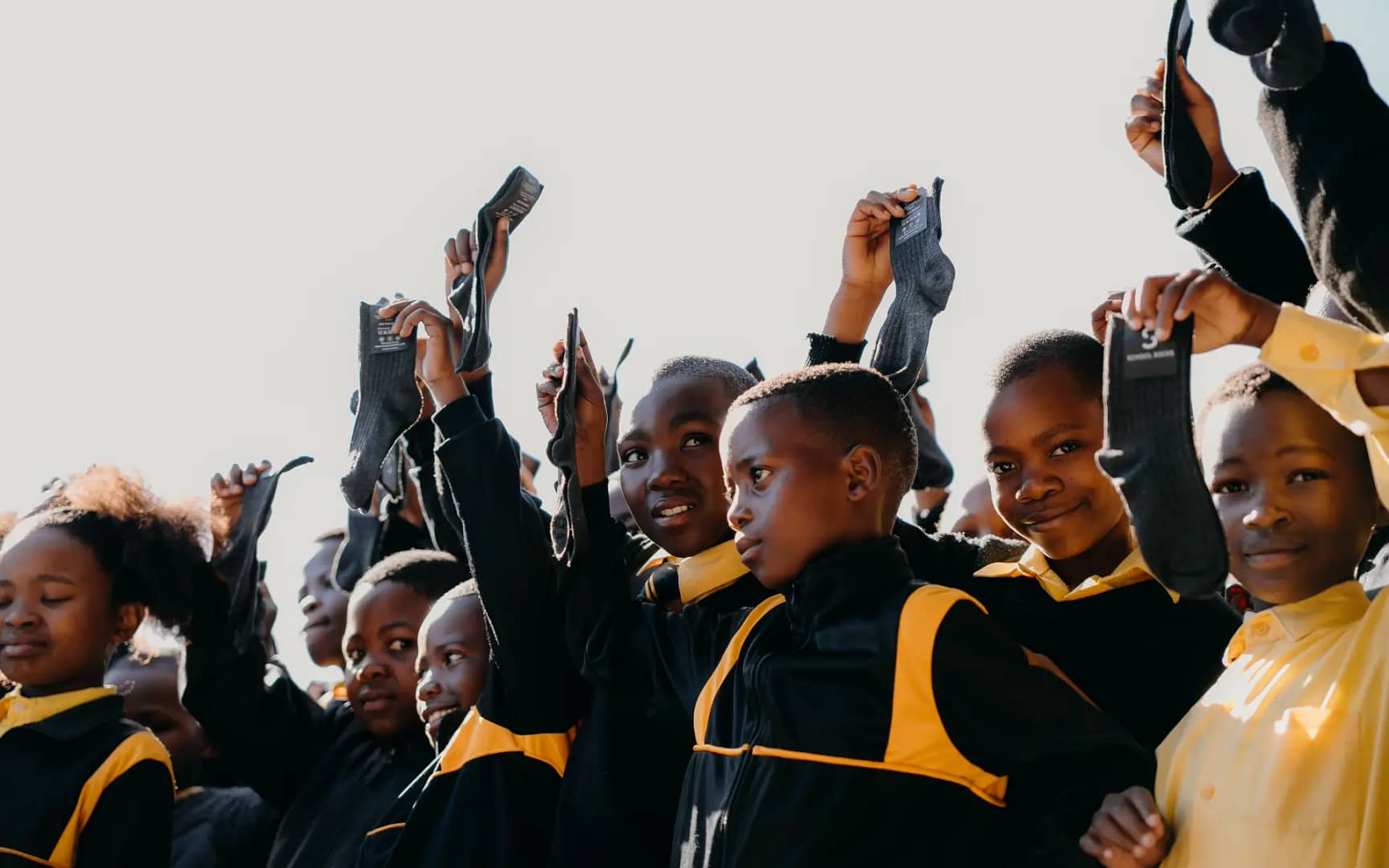 Group of children in black and yellow uniforms raising sexy socks above their heads in celebration.